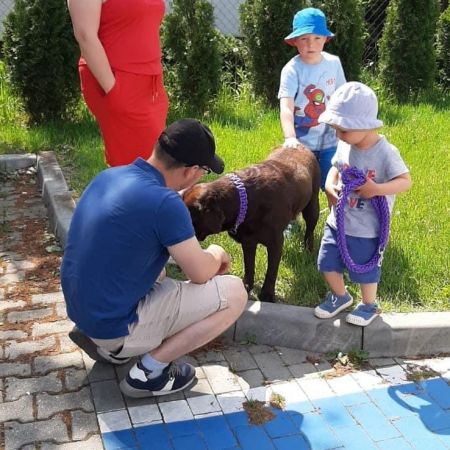 Kucający mężczyzna przy psie głaskanym przez dziecko